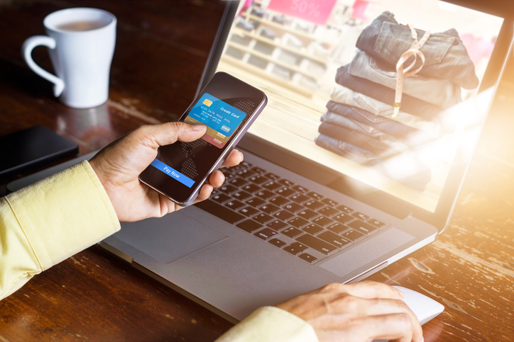 Mobile payments, Man using smartphone  shopping online, laptop screen showing products for customers.