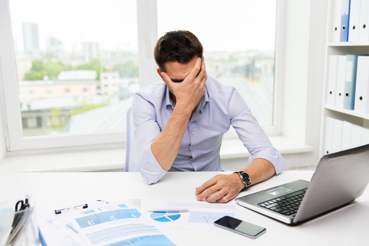 business, people, fail, paperwork and technology concept - businessman with laptop computer and papers working in office